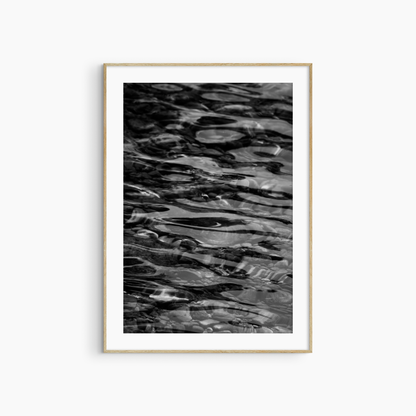 Dark water over pebbles photography print, black and white abstract wall art, coastal ripple print