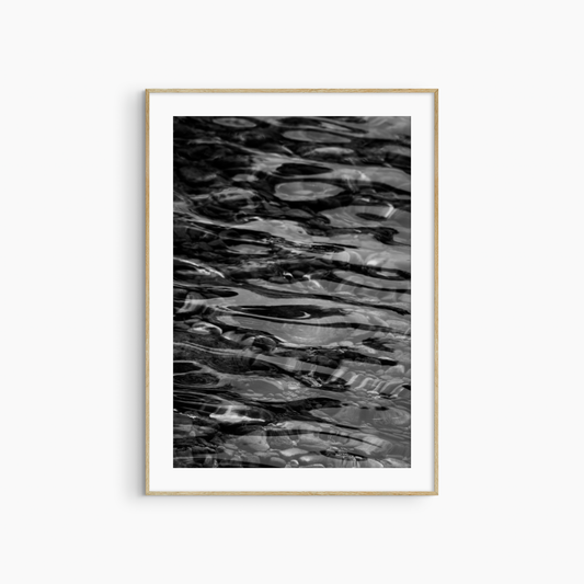 Dark water over pebbles photography print, black and white abstract wall art, coastal ripple print