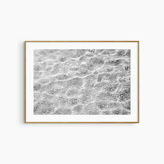 Shallow water over pebble shore photography print, black and white abstract wall art, coastal light print